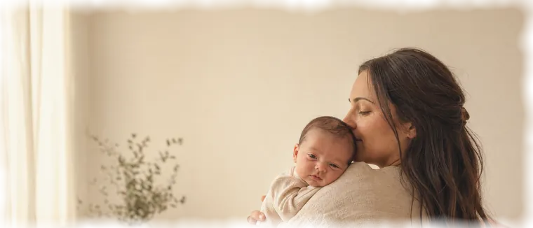 Una mamma bacia il suo neonato sulla testa.